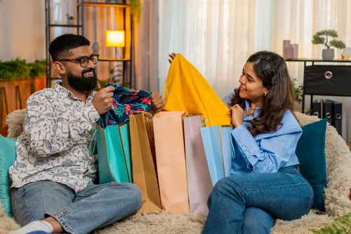 A man and woman opening Black Friday shopping bags at home.