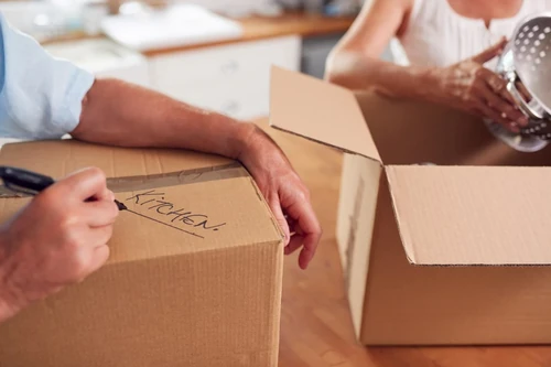 A man and woman label boxes as they pack items to put in their self storage unit.