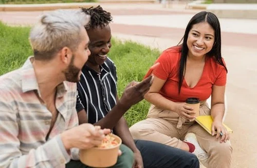 Diverse people having fun eating take away food outdoor in the city.